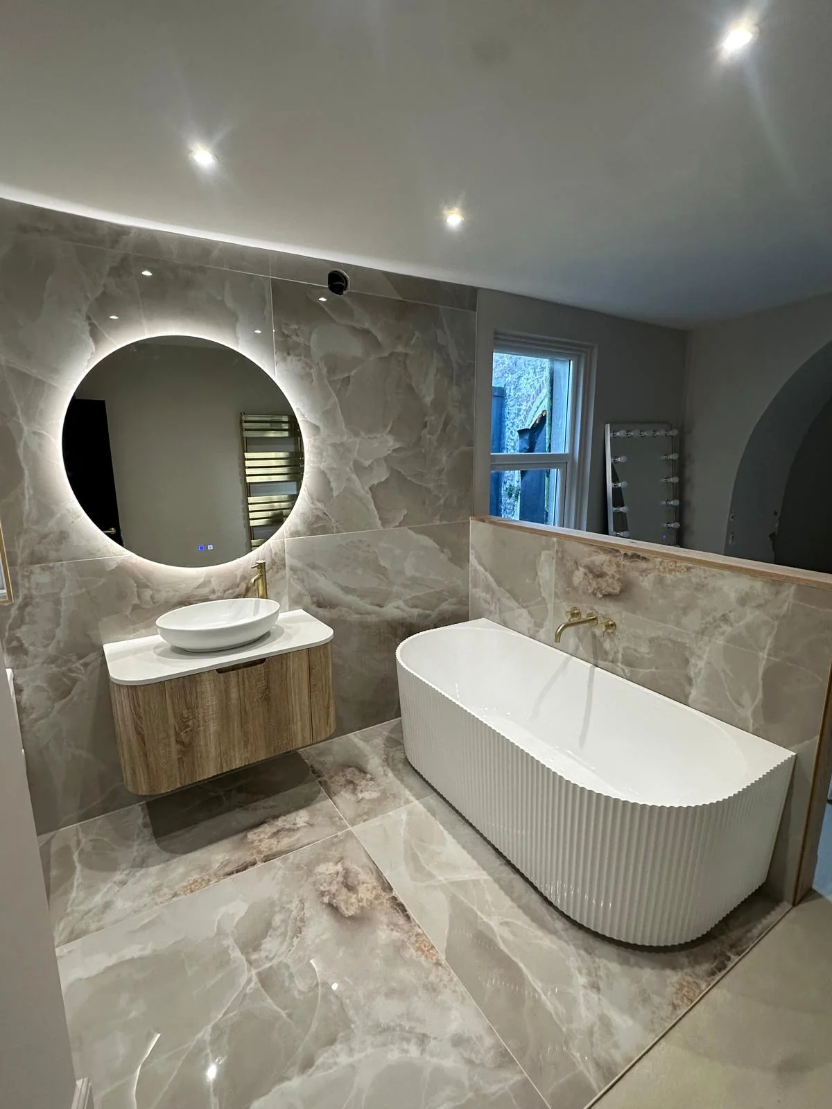 Completed luxury ensuite with fluted bath, marble tiles, and brushed gold fixtures