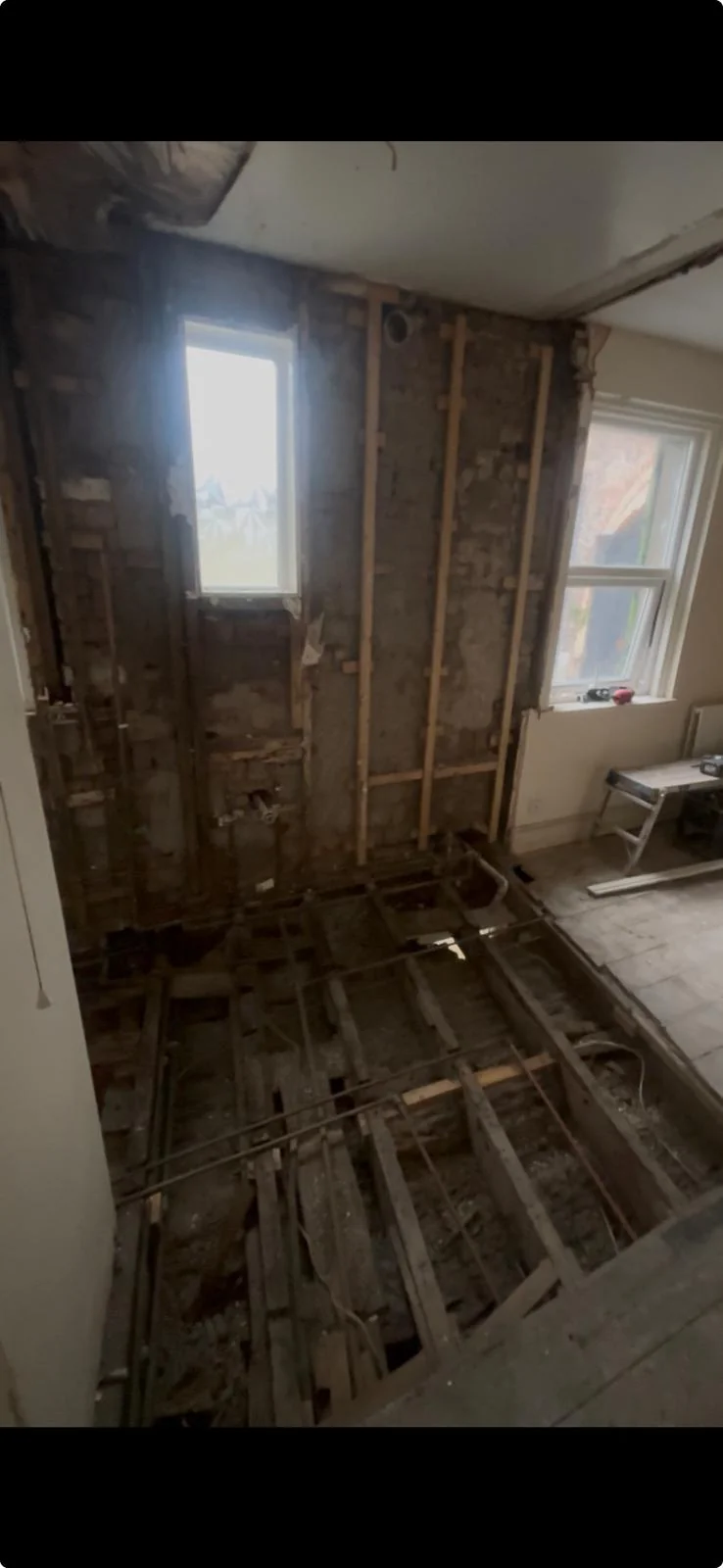 Bathroom renovation in progress showing stripped back timber joists and masonry